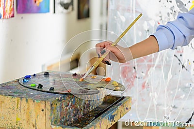 cropped image of artist taking paint from palette Stock Photo