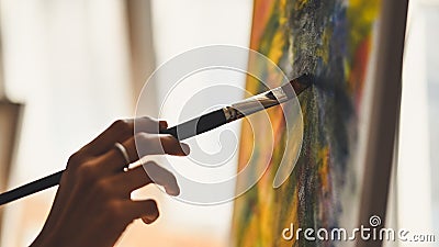 Cropped image of artist woman's hand drawing an oil color on canvas by paint brush at the modern art studio. Stock Photo