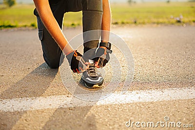 Cropped image of an athlete runner tying shoelaces, standing on a treadmill of the urban glass city bridge, ready for Stock Photo