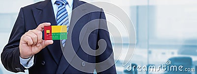 Cropped image of businessman holding plastic credit card with printed flag of Guinea Bissau. Background blurred Stock Photo