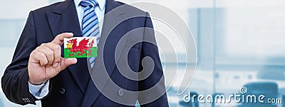 Cropped image of businessman holding plastic credit card with printed flag of Wales. Background blurred Stock Photo