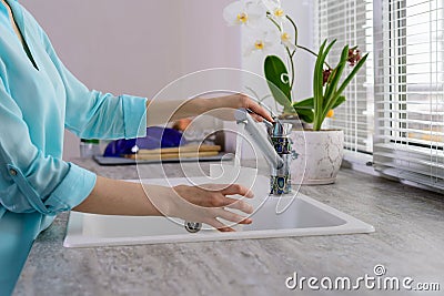 Cropped image of female hands with a Cup pours filtered tap water in the kitchen Stock Photo