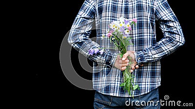 Cropped image hands of man behind his back with bouquet of wild flowers. Surprise, gift for your loved one, woman`s day, valentin Stock Photo