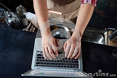 cropped image of a male bartender using a laptop. Stock Photo