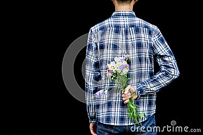 Cropped image man`s hand behind his back with bouquet of wild flowers. Touchingly surprise, gift for your loved one, woman`s day Stock Photo