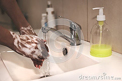 African-American woman washes hands. Cropped image of person washing hands at sink in bathroom, Coronavirus hand washing for clean Stock Photo