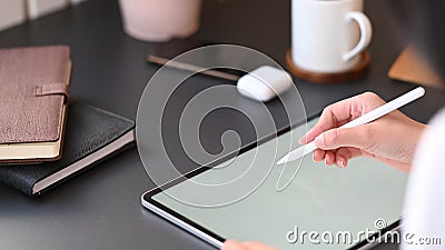 Cropped image of secretary woman`s hand holding stylus pen wile writing on computer tablet. Stock Photo