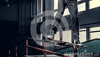Cropped image of a skateboarder performing a trick on grind rail in skate park indoor. Stock Photo