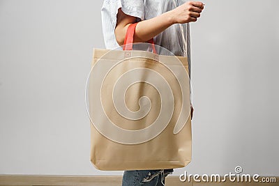 Cropped image of woman holding beige shopping bag in studio Stock Photo