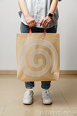 Cropped image of woman holding beige shopping bag in studio Stock Photo