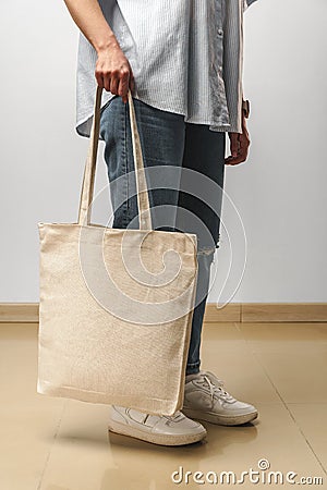 Cropped image of woman holding beige shopping bag in studio Stock Photo