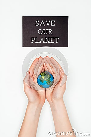 cropped image of woman holding earth model in hands under sign save our planet Stock Photo