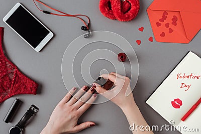 cropped image of woman painting nails with red polish, notebook with words Stock Photo