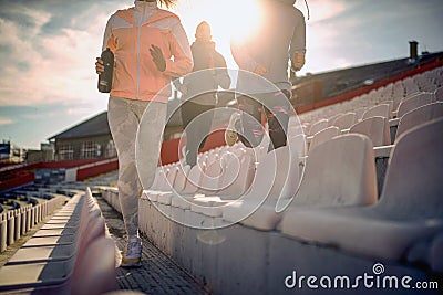 Cropped image of young adults running between rows of seats at the stadium Stock Photo