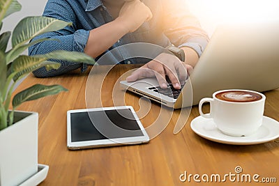 Cropped image young man sitting at the table with cup of coffee, digital tablet and computer, Stock Photo