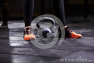 Cropped image of young woman, legs in the black leggings, orange sneakers and kettlebell. Crossfit workout Stock Photo