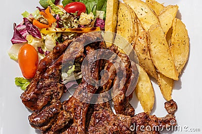 Cropped. Lunch on the plate with lamb, potato and salad on the table outside on the balcony. Greek traditional dishes. Food. Stock Photo