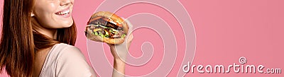 Close up portrait of a hungry young woman eating burger isolated over pink background Stock Photo