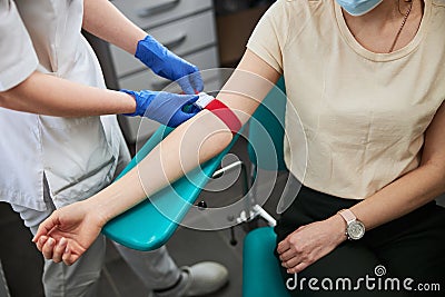 Phlebotomy technician tightening the elastic band on the patient arm Stock Photo
