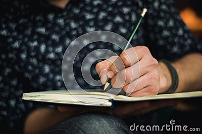 Man writing in journal with a pencil Stock Photo