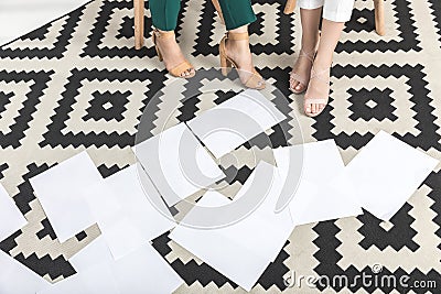 cropped shot of businesswomen sitting near blank papers on floor Stock Photo