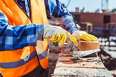 Cropped shot of construction worker in protective gloves laying bricks Stock Photo