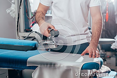 cropped shot of dry cleaning worker using industrial iron Stock Photo