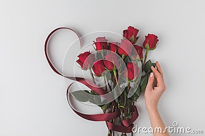 Female hand and bouquet of red roses with ribbon for st valentines day holiday isolated on white Stock Photo