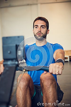 Serious about personal fitness. Cropped shot of a handsome young man working out on a rowing machine in the gym. Stock Photo