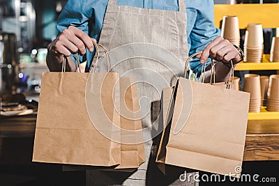 cropped shot of male barista in apron holding paper bags Stock Photo