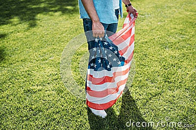 cropped shot of man holding american flag while standing on grass Stock Photo