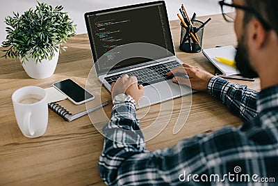 cropped shot of man in plaid shirt using laptop with program code Editorial Stock Photo