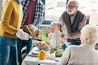 cropped shot of man and woman carrying turkey for thanksgiving dinner while excited family looking Stock Photo