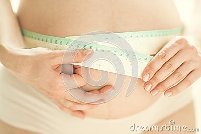 Cropped shot of pregnant woman measuring herself with flexible ruler Stock Photo