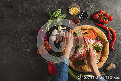 cropped shot of woman cutting cooked italian pizza with fresh ingredients Stock Photo