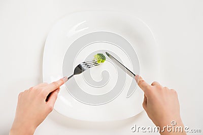 cropped shot of woman eating small piece of broccoli with fork and knife Stock Photo