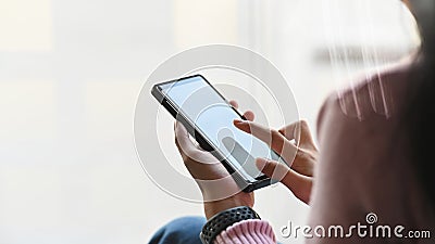 Cropped shot of woman hand while using a smartphone. Pointing finger on white blank screen. Stock Photo