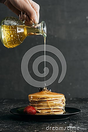 cropped shot of woman pouring maple syrup onto stack of freshly Stock Photo