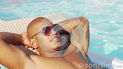 Cropped sliding shot of a happy African man relaxing at the poolside Stock Photo