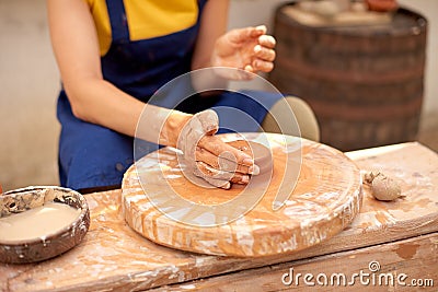 Cropped unrecognizable ceramist woman working with potter`s wheel in cozy workshop Stock Photo