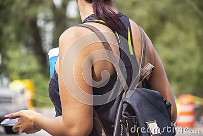 Cropped unrecognizable woman wth summer teeshirt and brown and black leather backpack holds soft drink and cell phone against a bo Stock Photo