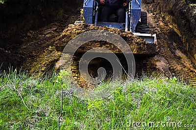 Cropped view of bulldozer loaded with soil in dirty pit with grass on foreground Stock Photo