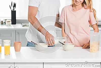 View of couple with bowls of cereal during breakfast at kitchen Stock Photo