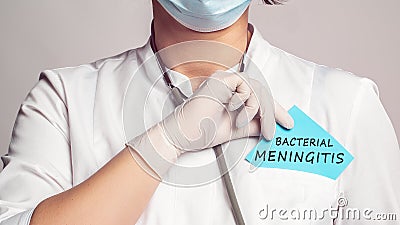 Cropped view of doctor in a white coat and sterile gloves holding a note with words - Bacterial Meningitis Stock Photo