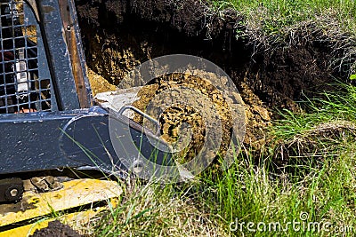Cropped view of excavator digging foundation pit in grassy field in countryside Stock Photo