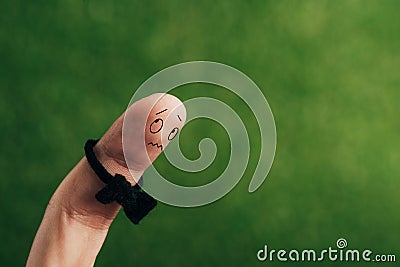 cropped view of frightened male finger in bow tie on green. Stock Photo