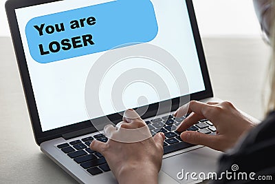 Cropped view of girl typing on laptop keyboard with you are loser message on screen, cyberbullying concept. Stock Photo