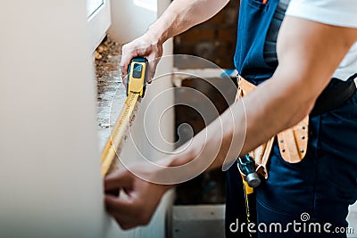 View of handyman measuring wall with yellow measuring tape Stock Photo