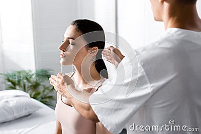 View of healer standing near woman and cleaning her aura Stock Photo