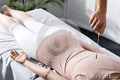 View of hypnotist standing near woman on massage table and holding green stone Stock Photo